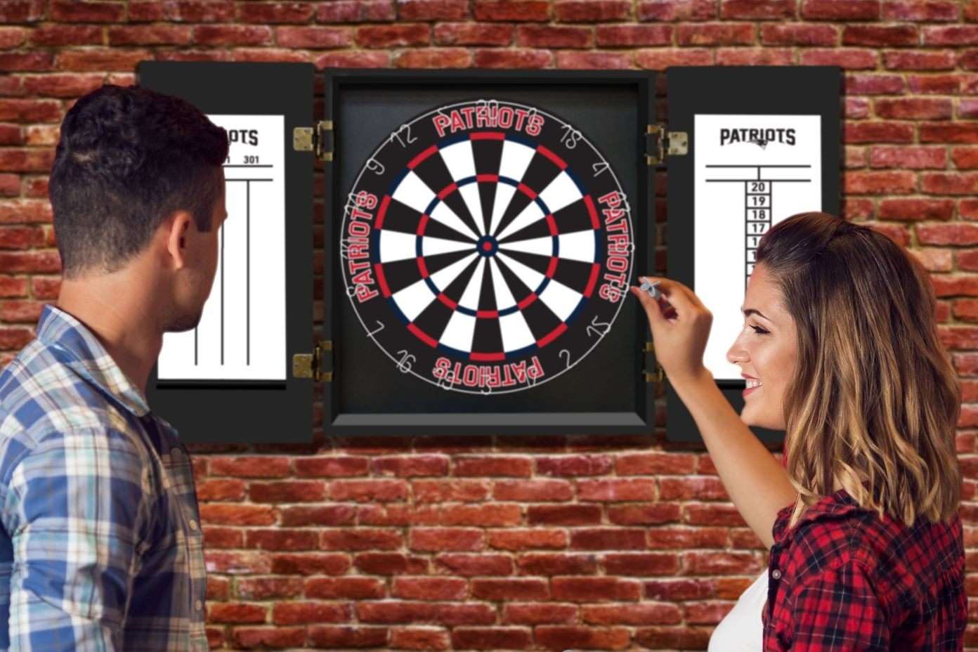 A woman throwing a dart at a Patriots dartboard, with a man watching.
