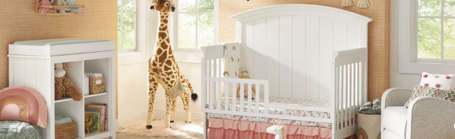 A nursery with a white crib, a giraffe, and a changing table.