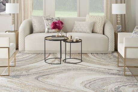 A living room with a cream-colored sofa, two side tables, and a patterned rug.
