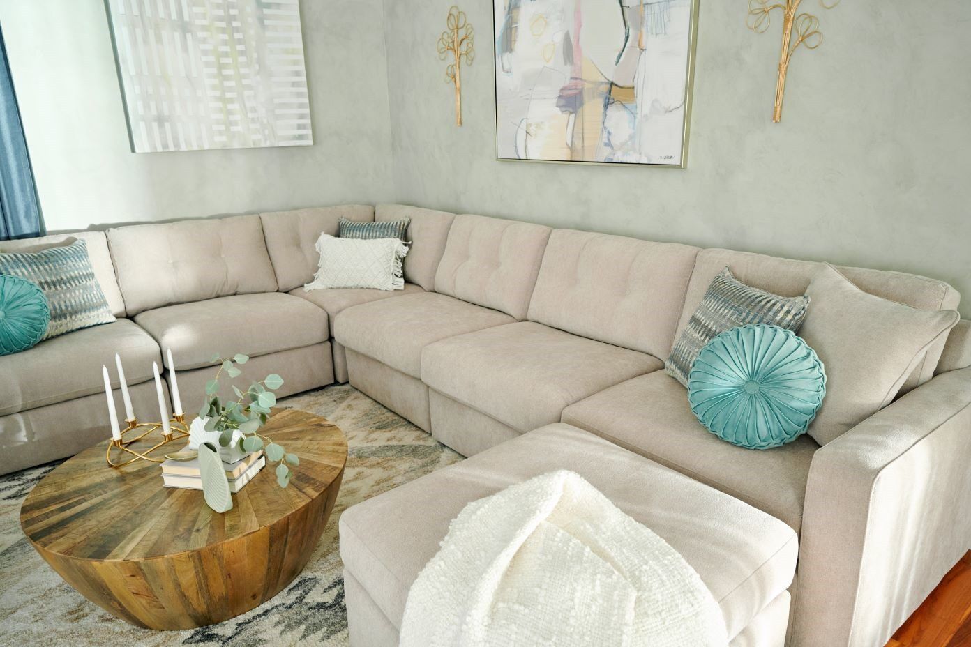 Beige sectional sofa with decorative pillows and a wooden coffee table.
