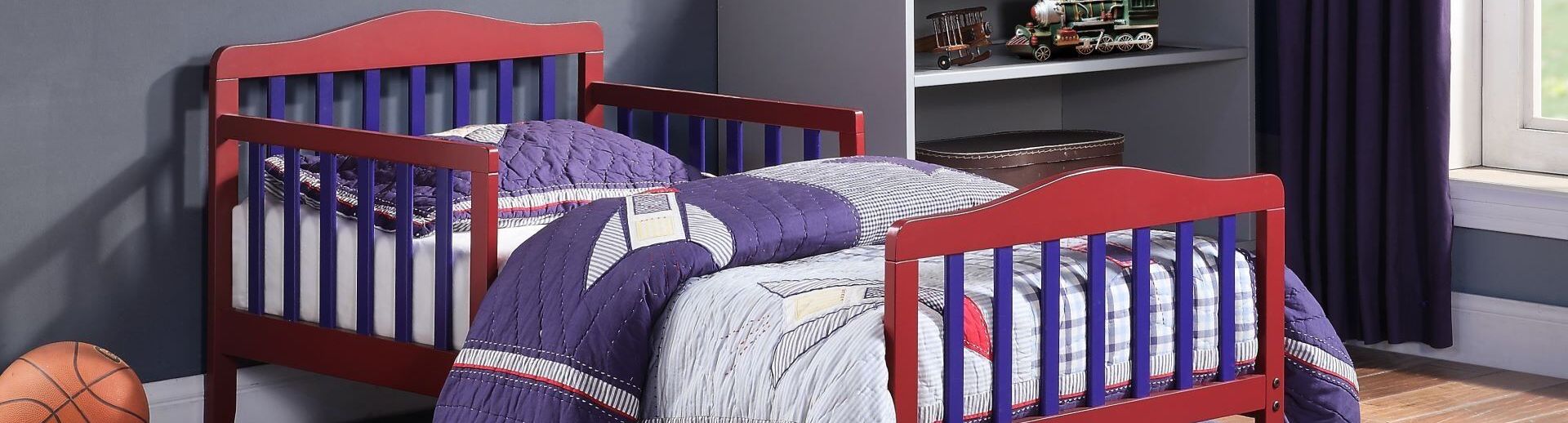 Red and blue toddler beds with a quilt on a blue rug.
