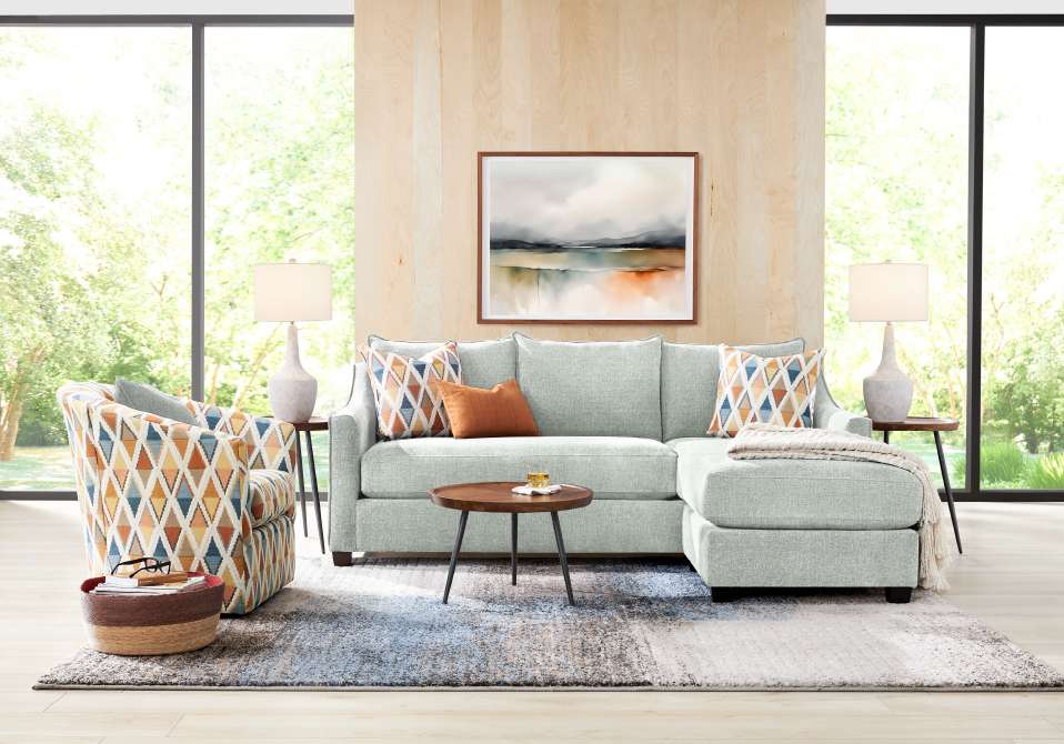 Living room with a light blue sectional sofa, patterned armchair, and a rug.
