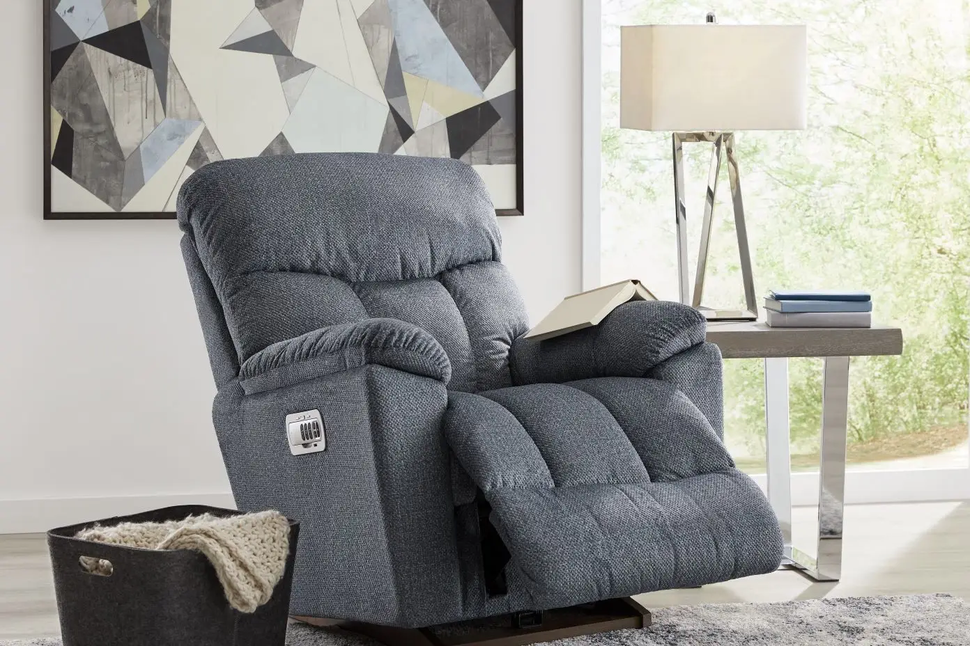 Blue upholstered recliner chair with a book on the arm.