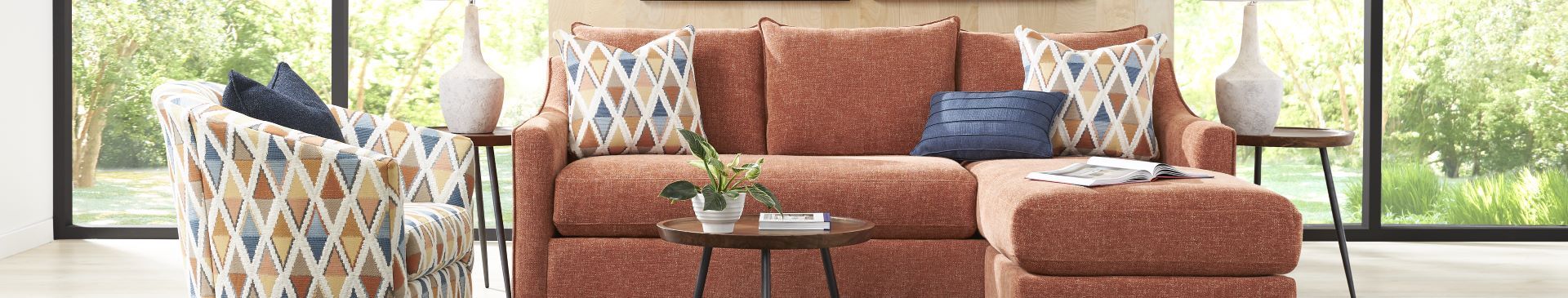 A sectional sofa with patterned pillows and a patterned armchair.