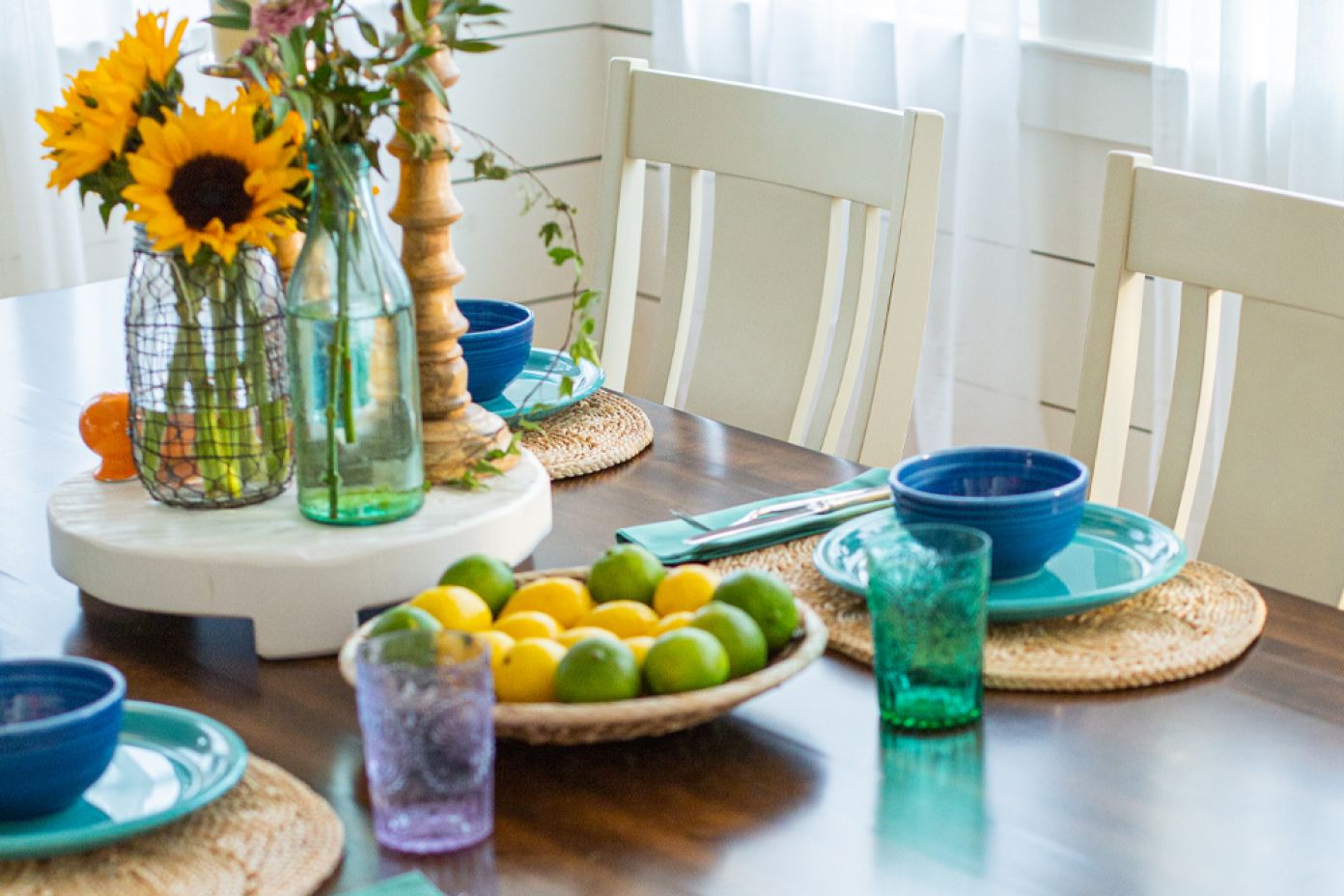 A dining table set with sunflowers, lemons, and blue tableware.
