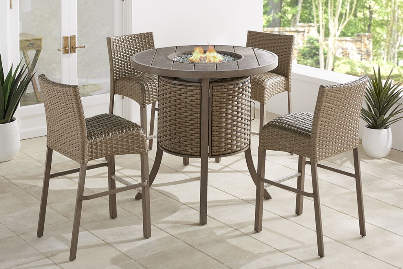 Outdoor fire pit table with four wicker bar stools.
