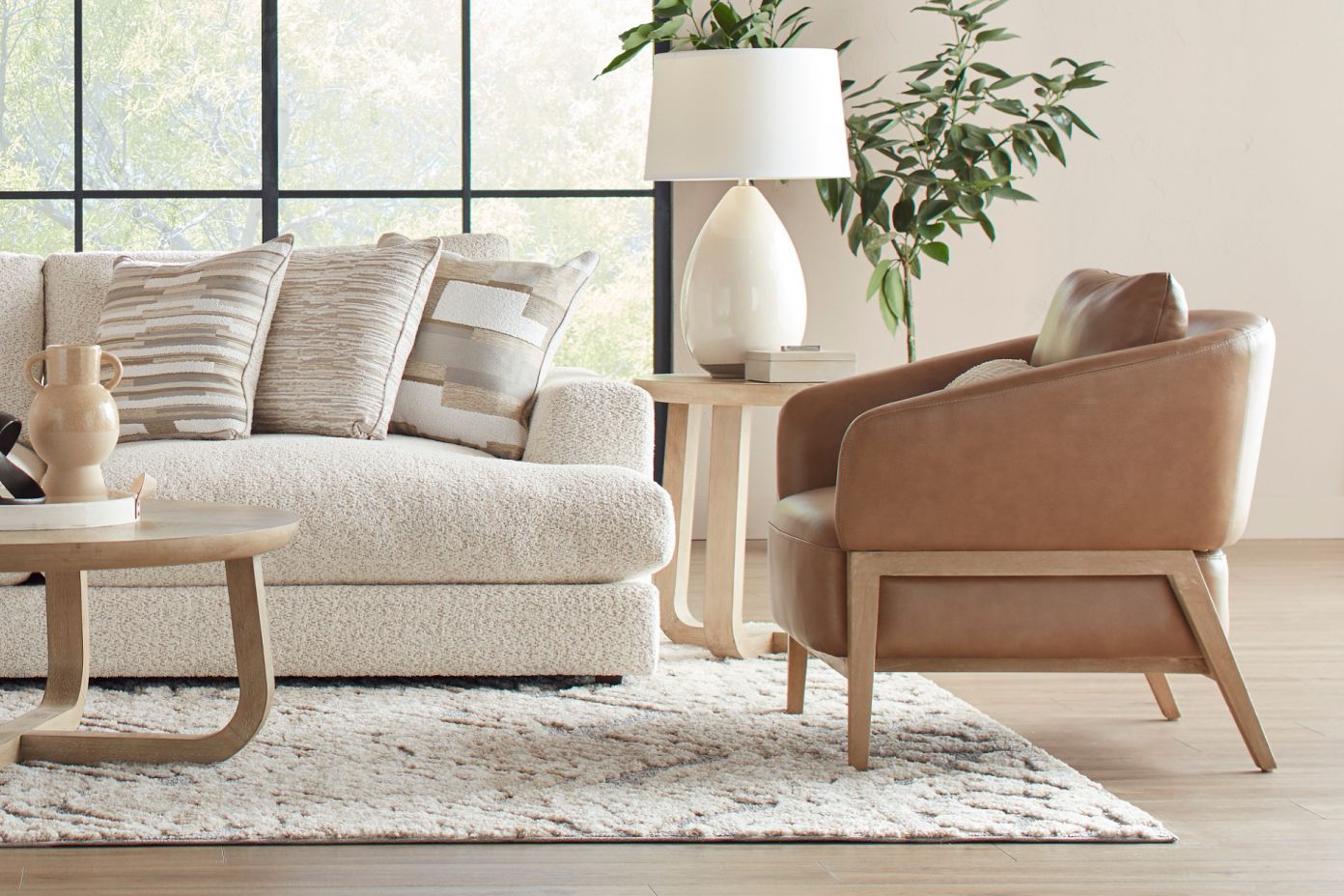 A living room with a cream-colored sofa, leather chair, and a rug.
