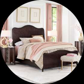 Bedroom set with a dark wood bed, nightstands, and a fluffy stool.
