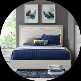 Modern bedroom set with a white bed frame, blue bedding, and artwork.
