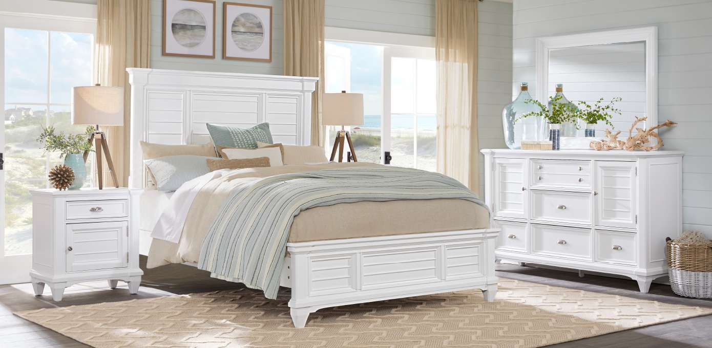 White bedroom furniture set with a bed, nightstand, and dresser.
