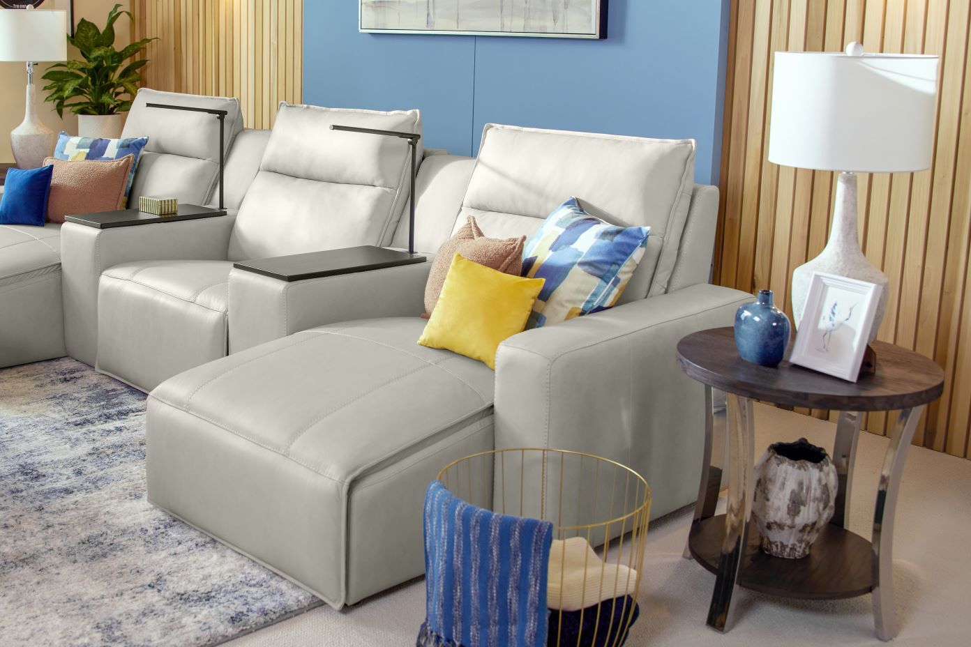 Gray leather sectional sofa with pillows and a side table.

