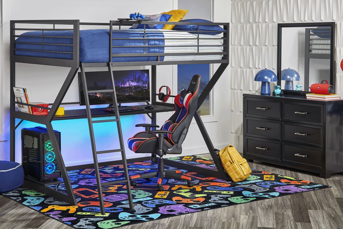 A black metal loft bed with a desk, gaming chair, and a colorful rug.
