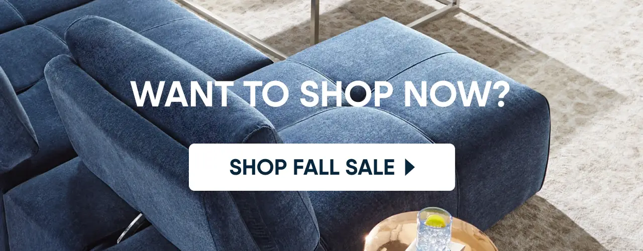WANT TO SHOP NOW? SHOP FALL SALE. A close-up of a blue upholstered sofa next to a light-colored rug.