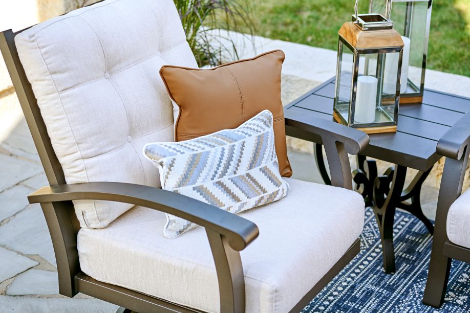 Outdoor chair with cushions and a side table with lanterns.
