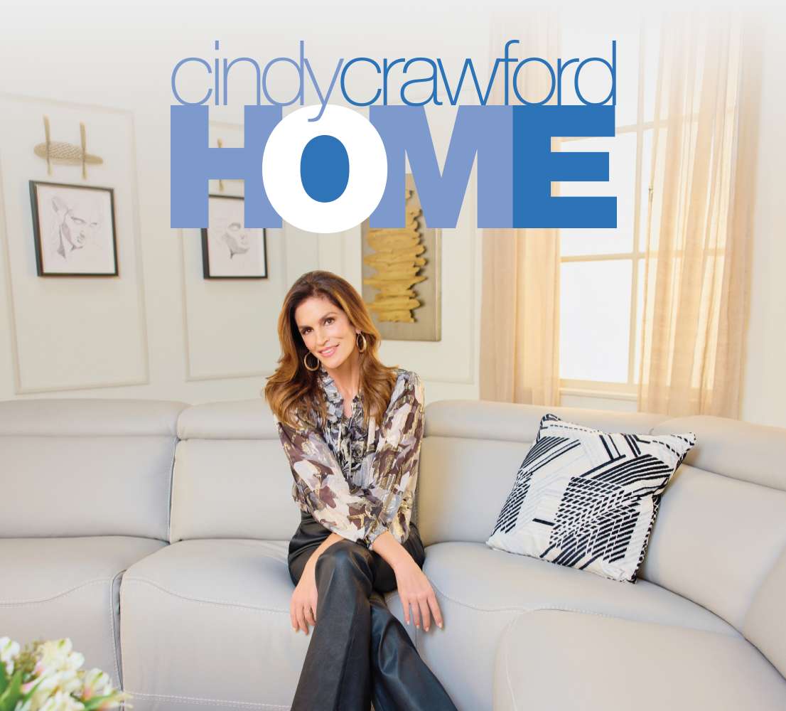 cindy crawford HOME. Cindy Crawford sitting on a light gray sofa.
