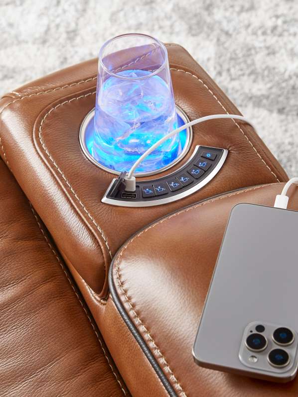 Brown leather recliner with a cup holder, control panel, and a phone charging.
