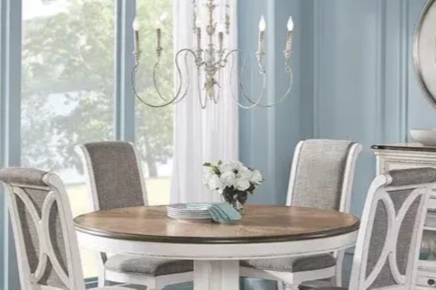 Dining room set with a round table, chairs, and a chandelier.

