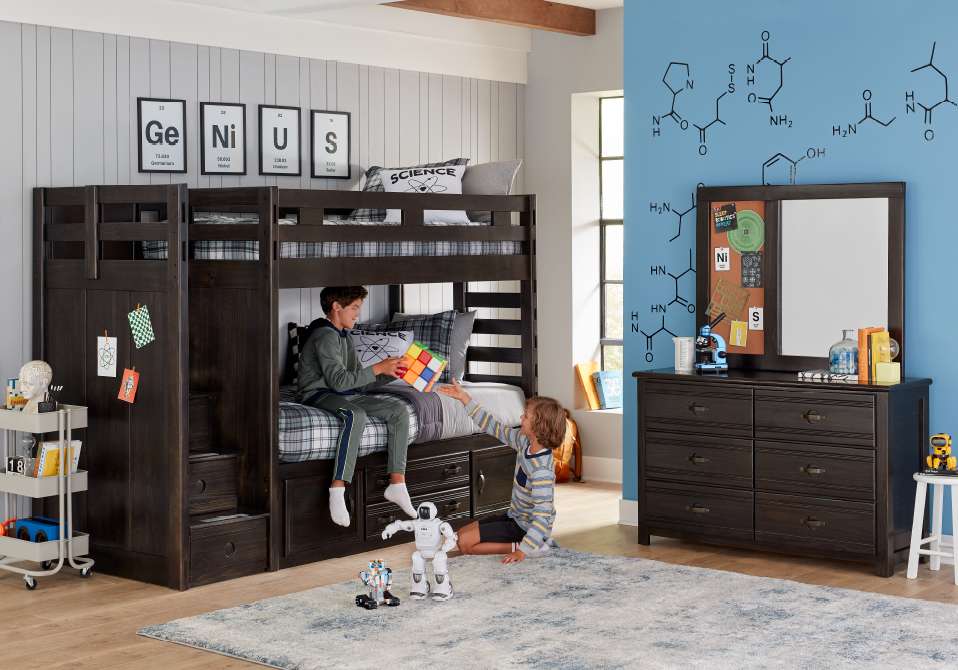 Two boys playing with a Rubik's cube in a science-themed bedroom with a bunk bed and dresser.