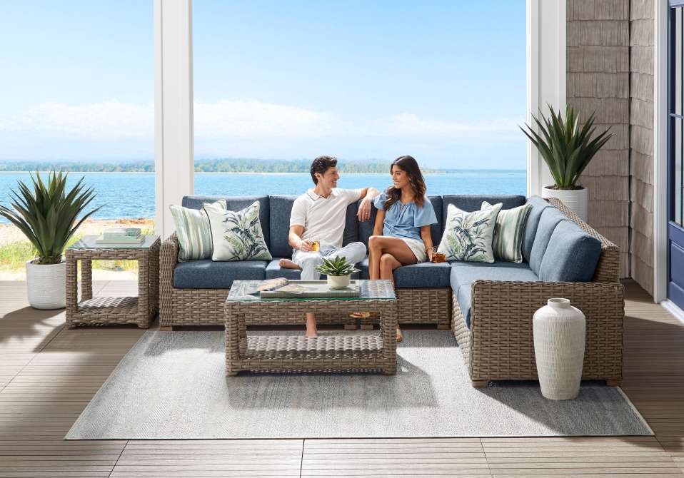 Outdoor sectional sofa with two people sitting, overlooking the ocean.