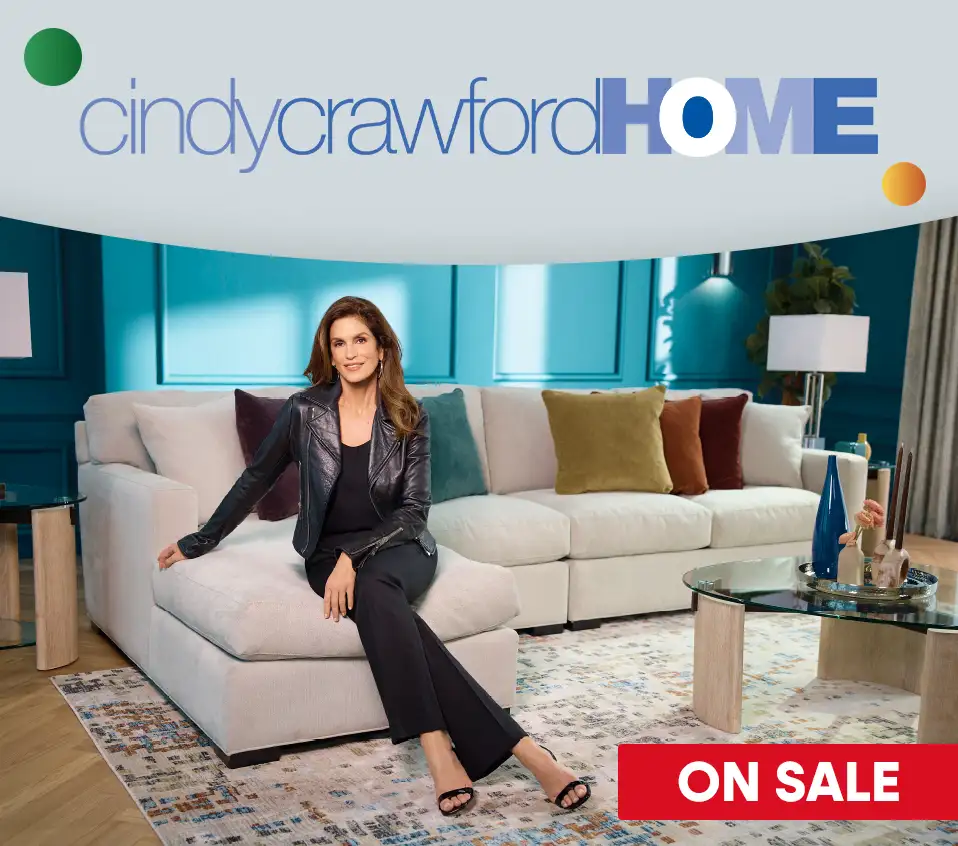 cindy crawford HOME ON SALE. Cindy Crawford sitting on a beige sectional sofa.