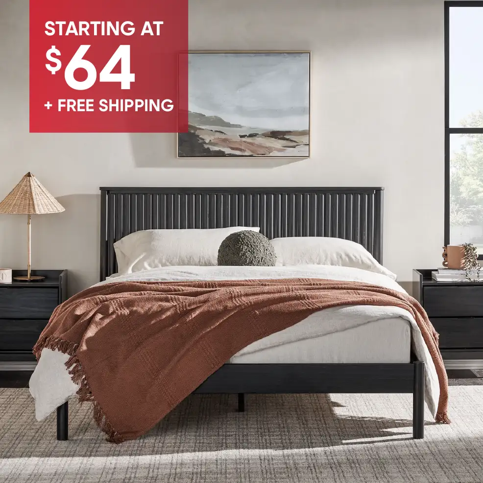 STARTING AT $64 + FREE SHIPPING. A black bed frame with a brown blanket.
