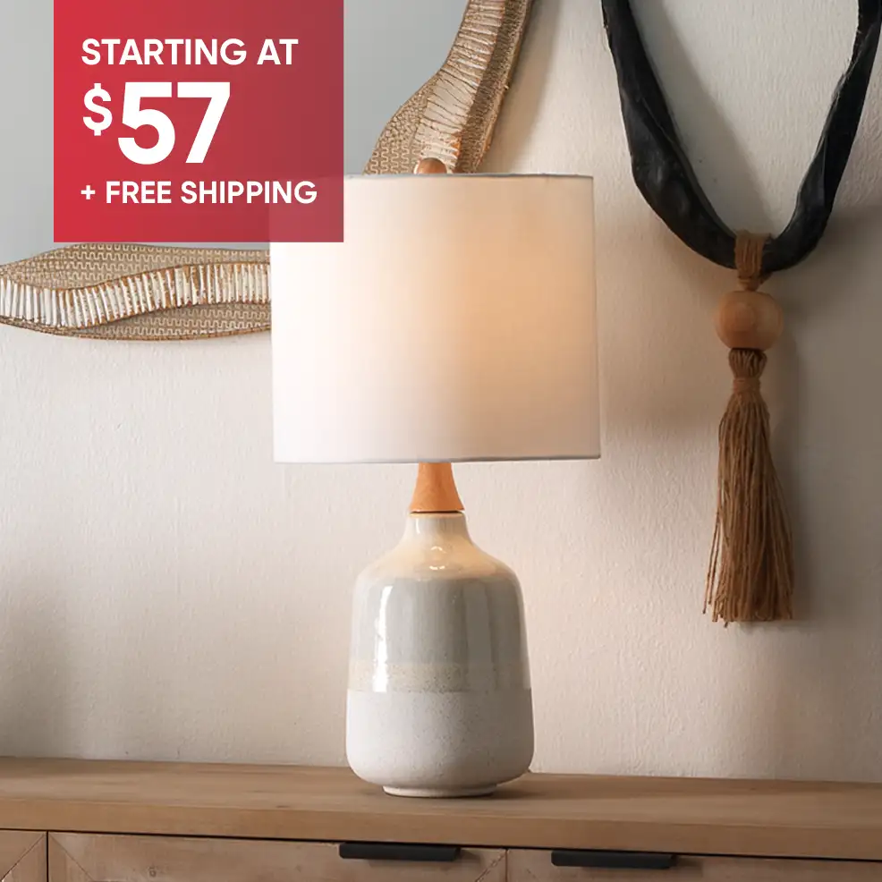 STARTING AT $57 + FREE SHIPPING. A ceramic table lamp with a white lampshade.
