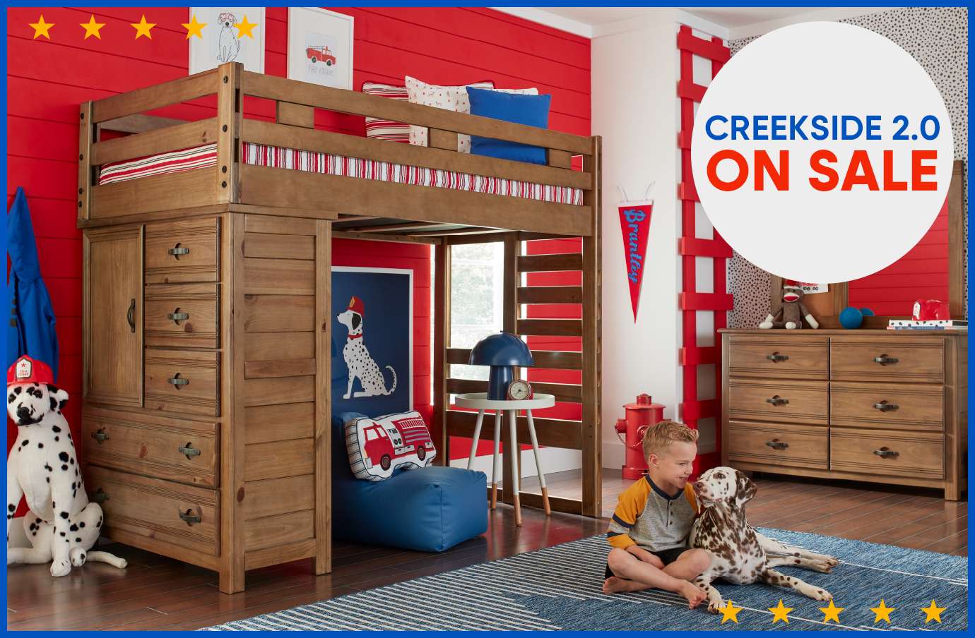 CREEKSIDE 2.0 ON SALE. A wooden loft bed with a dresser, a boy, and a Dalmatian dog in a red-themed room.
