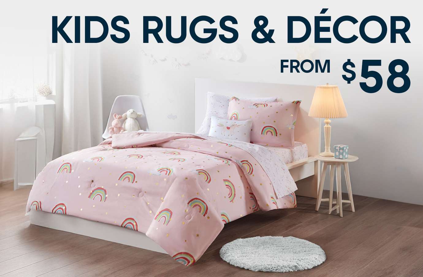 KIDS RUGS & DÉCOR FROM $58. A bed with pink rainbow bedding and a small rug.
