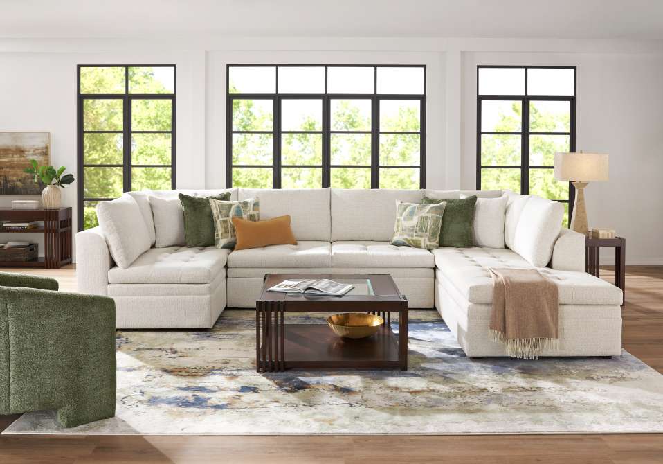 A large, cream-colored sectional sofa with decorative pillows in a bright living room.
