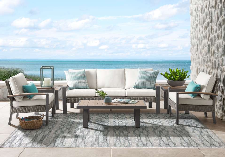 Outdoor furniture set on a patio overlooking the ocean.
