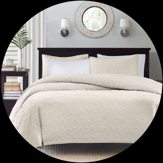 Cream-colored bedspread and pillows on a dark wooden bed frame.
