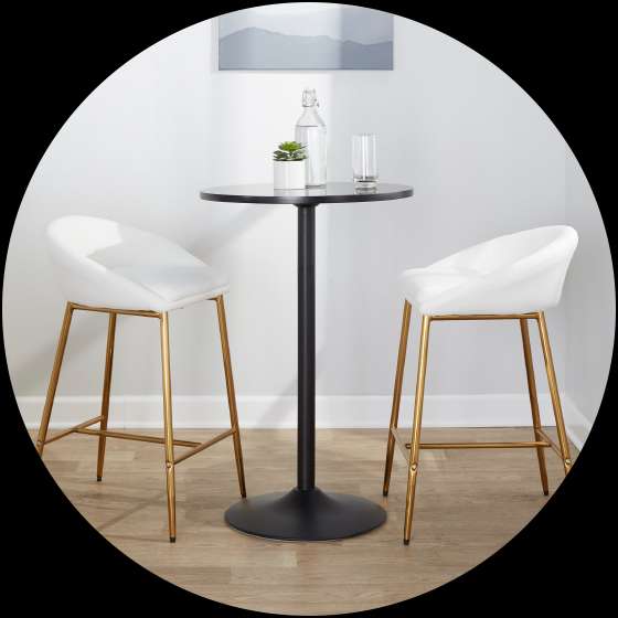 Two white bar stools with gold legs and a black table with a glass and plant.
