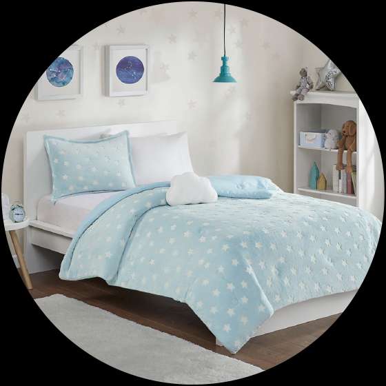 A bed with a blue star-patterned comforter and pillow, with a cloud-shaped pillow.
