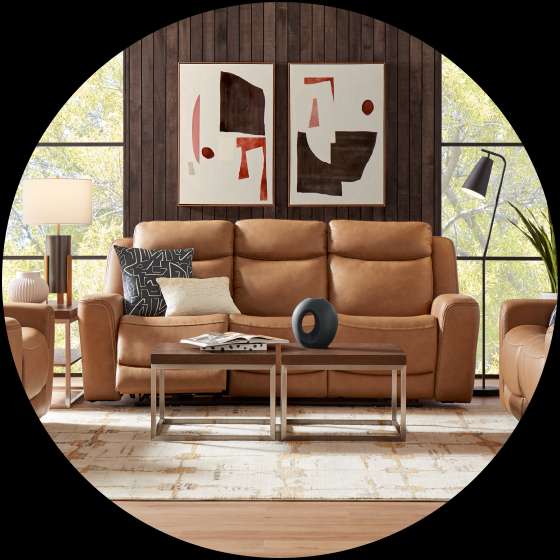 A living room with a brown leather sofa, two square coffee tables, and abstract art.
