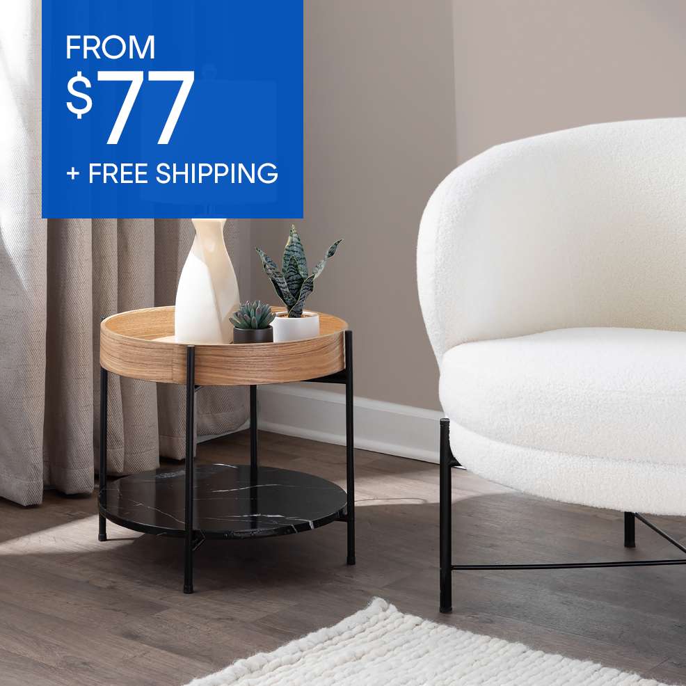 FROM $77 + FREE SHIPPING. A round side table with a wooden top and black marble bottom, next to a white chair.
