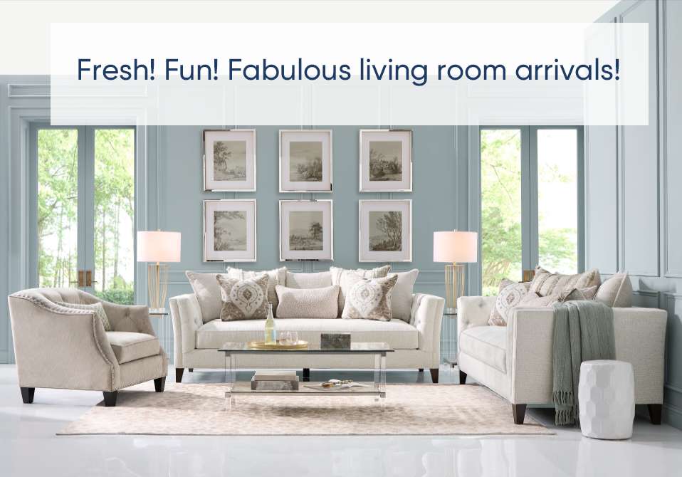 Fresh! Fun! Fabulous living room arrivals! A living room with light-colored furniture, lamps, and artwork.
