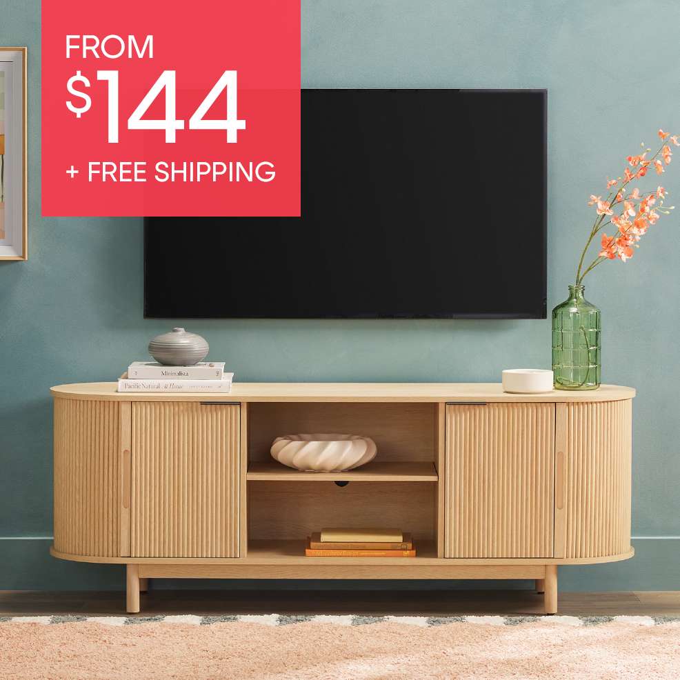 FROM $144 + FREE SHIPPING. A light wood TV stand with a TV above it.
