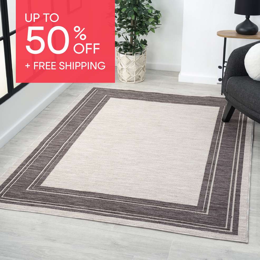 Up to 50% off + free shipping. A rectangular rug with a dark border on a light floor.
