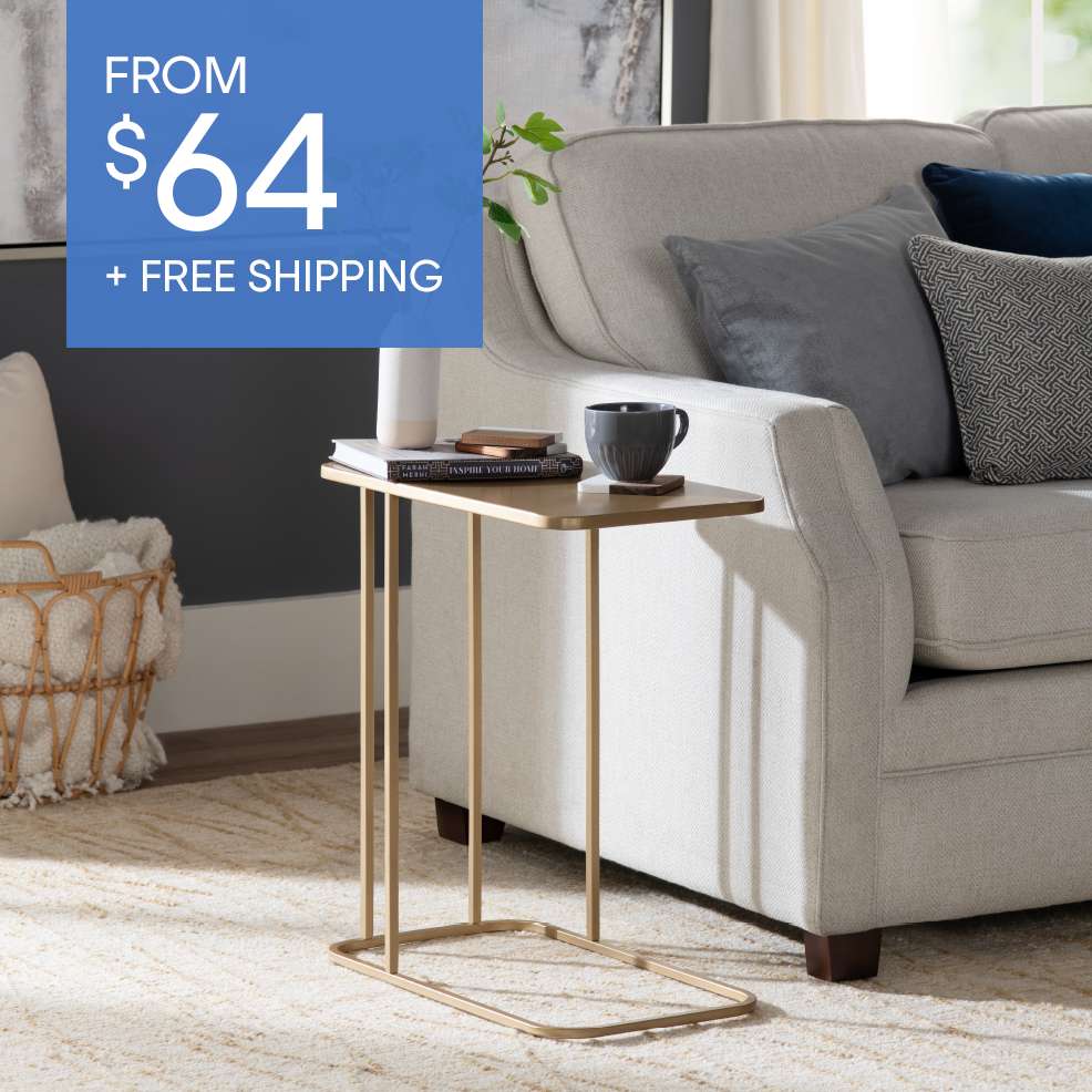 FROM $64 + FREE SHIPPING. A gold side table next to a light gray couch.
