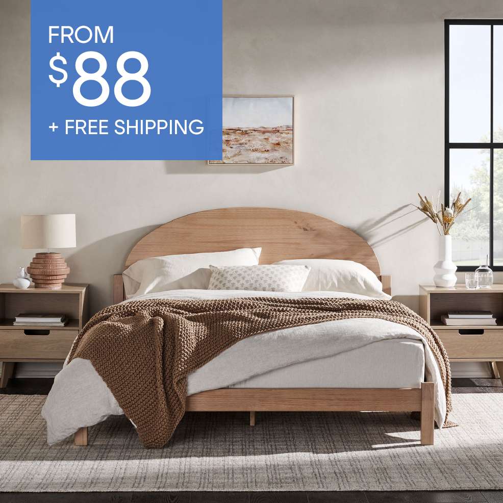 FROM $88 + FREE SHIPPING. A wooden bed frame with a brown blanket and white bedding.
