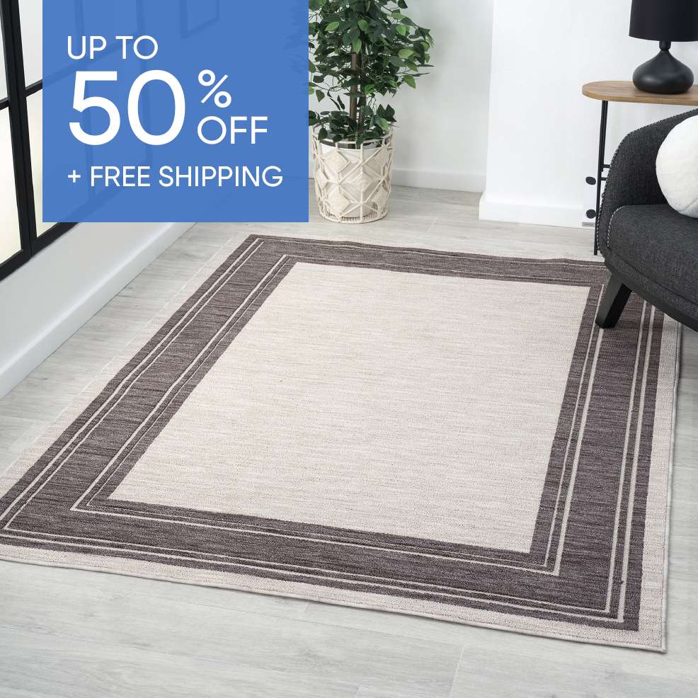 UP TO 50% OFF + FREE SHIPPING. A rectangular rug with a brown border on a light-colored floor.
