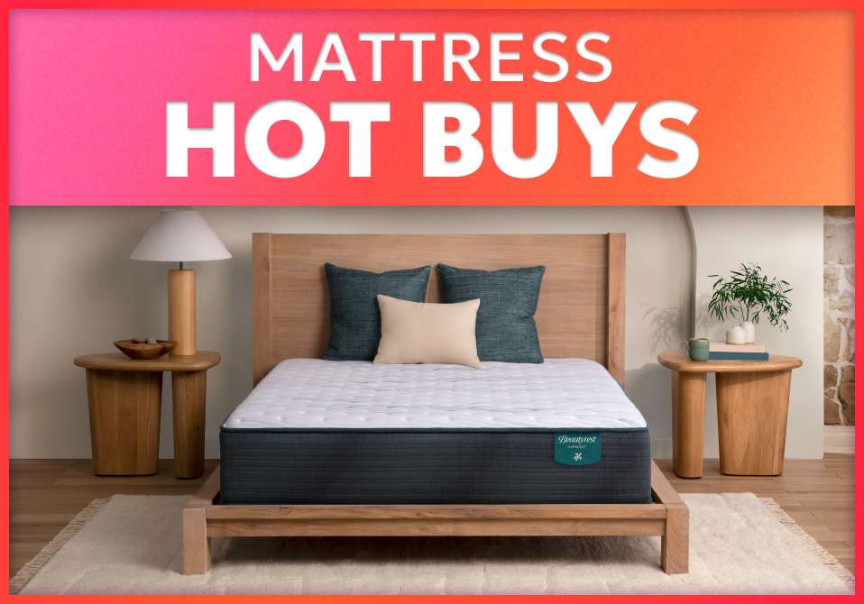 MATTRESS HOT BUYS. A bed with pillows and two wooden side tables.
