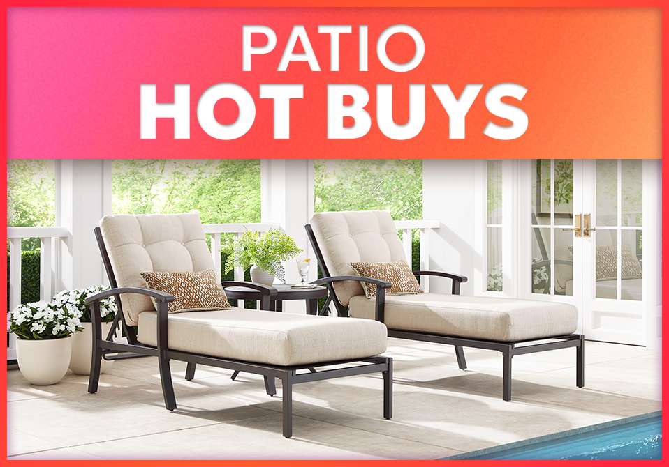 PATIO HOT BUYS. Two beige chaise lounge chairs on a patio.
