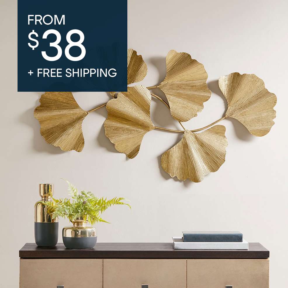 FROM $38 + FREE SHIPPING. A gold metal leaf wall decor above a wooden cabinet with decor.
