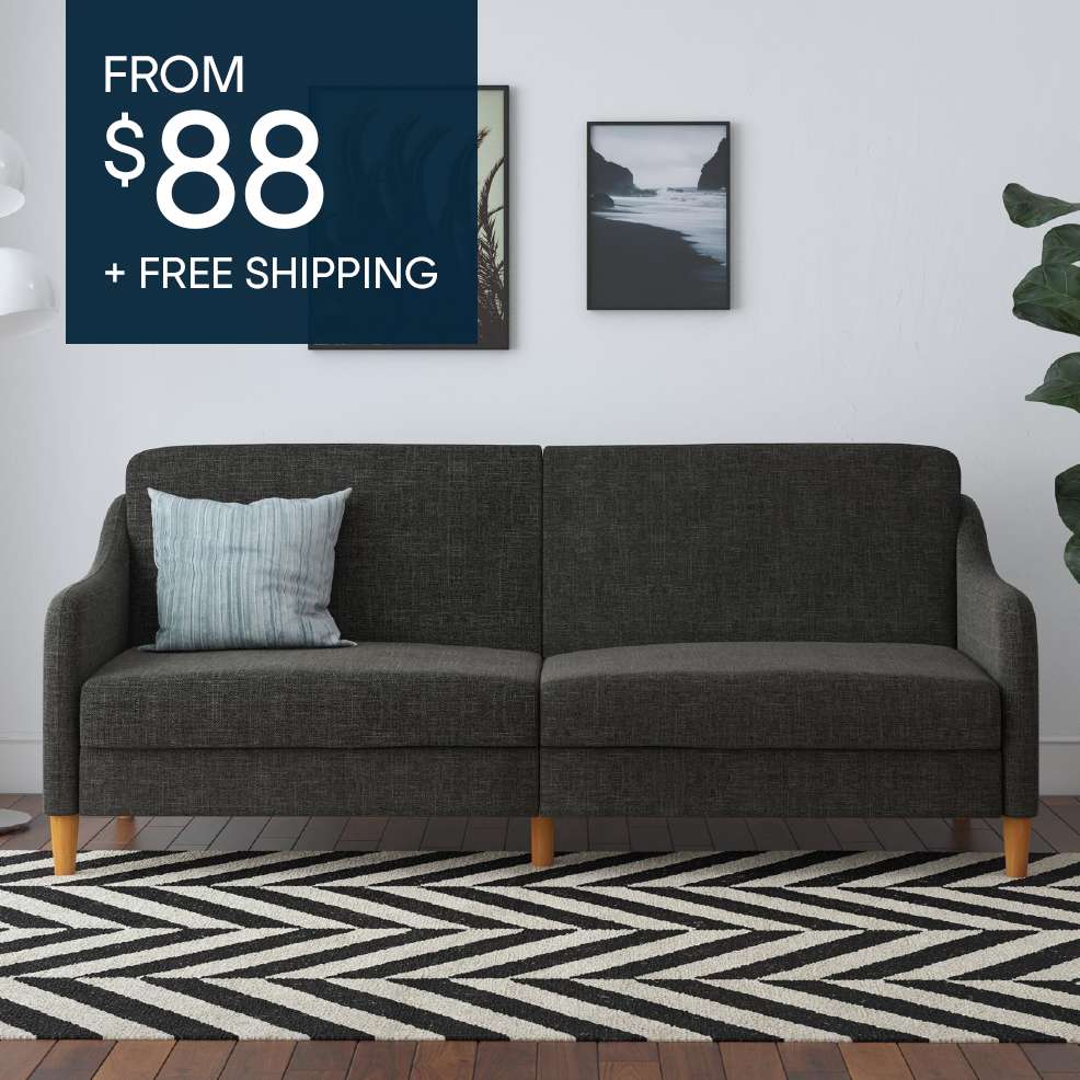 FROM $88 + FREE SHIPPING. A dark gray sofa with a light blue pillow on a black and white rug.
