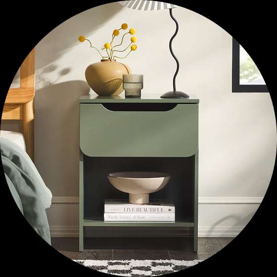 Green nightstand with a vase, lamp, and books.
