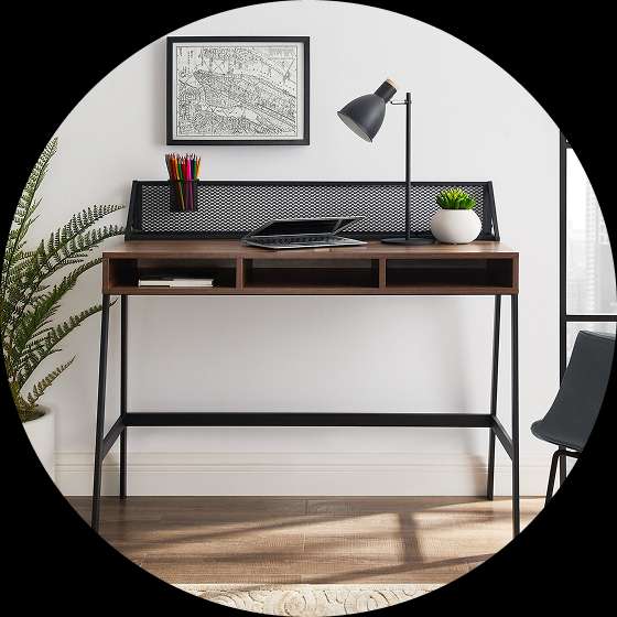 A wooden desk with a black metal frame, a lamp, and a plant.
