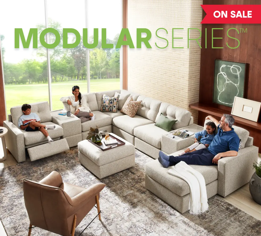MODULAR SERIES ON SALE: A family relaxes on a large, beige modular sectional sofa in a bright, modern living room.