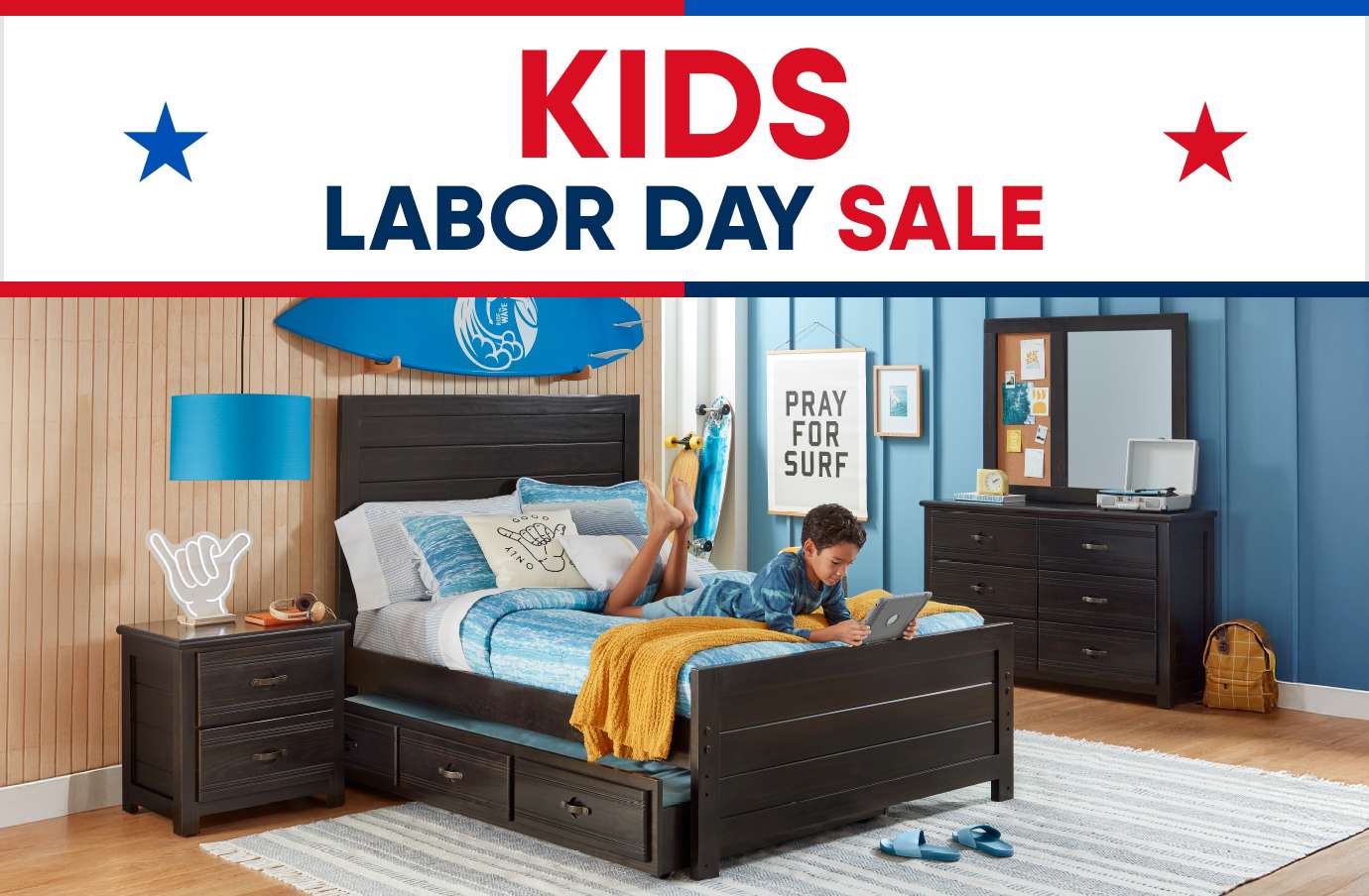 KIDS LABOR DAY SALE. A bedroom with a bed, dresser, and a boy using a tablet.
