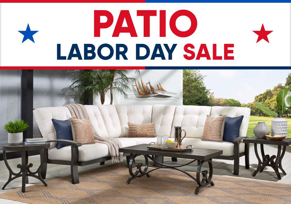 PATIO LABOR DAY SALE. A sectional sofa with pillows and a coffee table on a rug.
